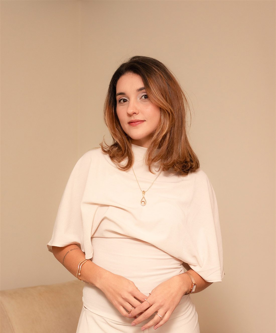 Nathalia Mancini de roupa bege, olhando para a câmera